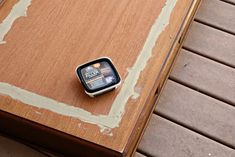 a cell phone sitting on top of a wooden table next to a tile floor with peeling paint