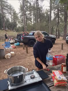 a woman standing in front of a stove top oven next to a table filled with food