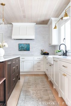 a large kitchen with white cabinets and wooden floors, along with an area rug on the floor