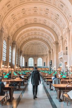 the inside of a library with tables and people sitting at their desks in it