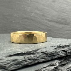 a gold wedding ring sitting on top of a rock