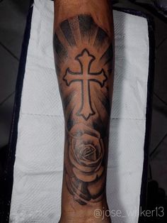 a man with a cross and rose tattoo on his arm