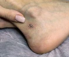 a woman's foot with a small smiley face tattoo on the side of her toe