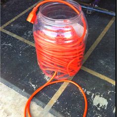 an orange cord connected to a large glass jar on the ground with other items around it