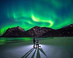 two people standing in the snow under an aurora bore