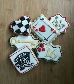 four decorated cookies on a wooden table with words and symbols in the shape of hearts