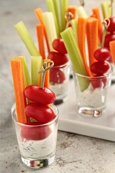 small cups filled with veggies and dips on a white tray next to each other