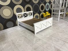 a white bed sitting on top of a wooden floor next to a wall covered in circles