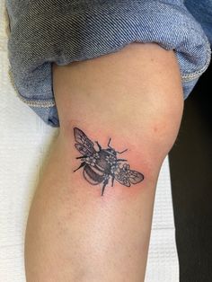 a small black and white bee tattoo on the leg