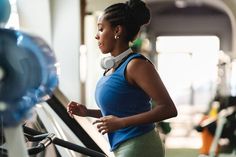 a woman running on a treadmill in a gym with headphones around her neck