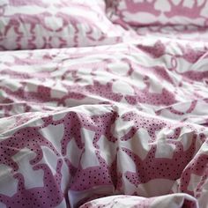 an unmade bed with pink and white bedspread on top of each other