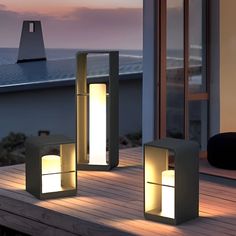 three outdoor lights sitting on top of a wooden deck next to a building near the ocean