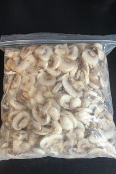 a bag filled with mushrooms sitting on top of a table next to a black surface