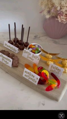 there are many different candies on the wooden tray with name tags in front of them