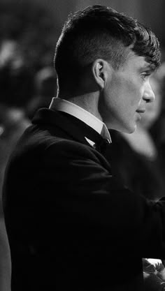 a black and white photo of a man in a suit with his hand on the tie