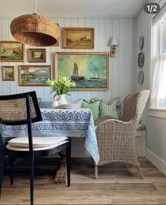 a dining room table with chairs and pictures on the wall above it, along with two wicker chairs