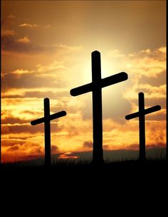 three crosses are silhouetted against the sunset