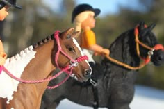 two toy figurines riding horses in the snow