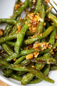 a white bowl filled with green beans covered in seasoning and topped with toasted nuts