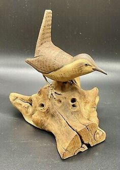 two wooden birds sitting on top of a piece of drift wood with holes in it