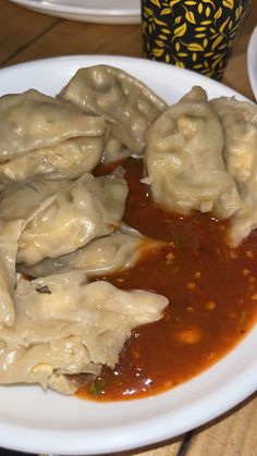 some dumplings are sitting on a white plate with sauce and ketchup in front of them