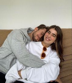 a man and woman laying on top of a couch next to each other, smiling at the camera