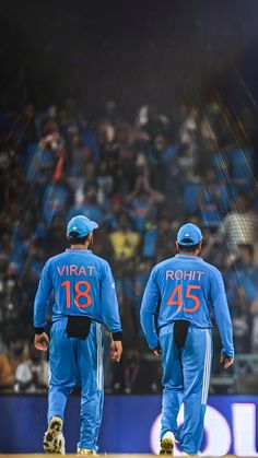 two men in blue uniforms walking on a field