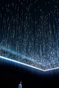 a man standing in the middle of a dark room with stars on the ceiling above him