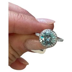 a woman's hand holding a ring with a large blue diamond in the center