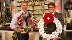 two men standing next to each other holding wreaths and christmas decorations in front of a tv screen