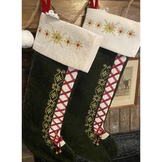 two christmas stockings hanging from a fireplace with red and white trimmings on them