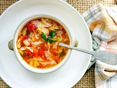 a white bowl filled with soup on top of a table next to a napkin and spoon