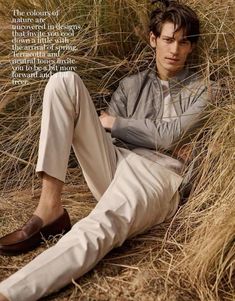 a man sitting on the ground next to tall grass