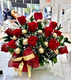 a vase filled with red roses and chocolates on top of a white countertop