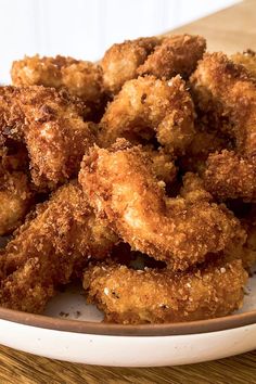 some fried food on a white plate on a wooden table with a brown and white bowl