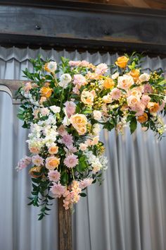 an arrangement of flowers is displayed in front of a curtain