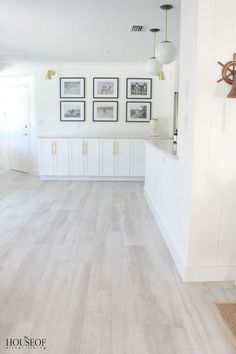 a white kitchen with wood floors and pictures on the wall