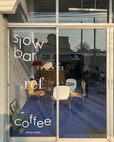 there is a coffee shop window with chairs and tables in front of the storefront