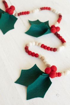 a necklace made out of felt and beads with holly leaves on the front, white background