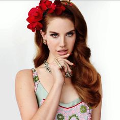 a woman with long red hair wearing a flower in her hair is posing for the camera