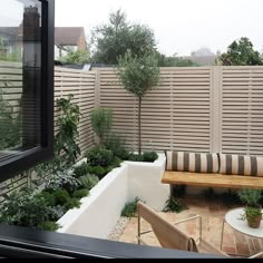 an outdoor seating area with wooden benches and potted plants on the side of a fenced in backyard