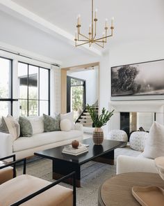 a living room with couches, chairs and a table in front of large windows