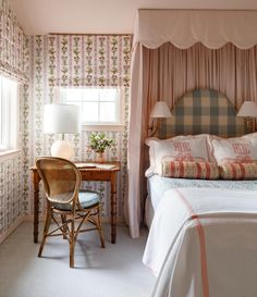 a bedroom with floral wallpaper and pink bedding in the corner next to a window