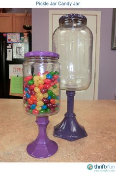 a glass jar filled with jelly beans next to a purple plastic candy dispenser