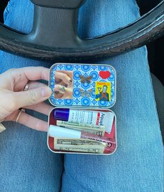 a person sitting in a car holding two small tins