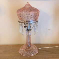 a pink glass table lamp sitting on top of a wooden table