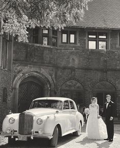 a bride and groom standing in front of an old car