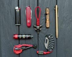 the contents of an outdoor survival kit laid out on a wooden surface with tools and gadgets