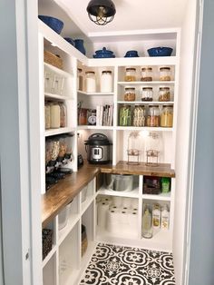 a kitchen with white cabinets and black and white tile flooring on the floor, along with lots of shelves