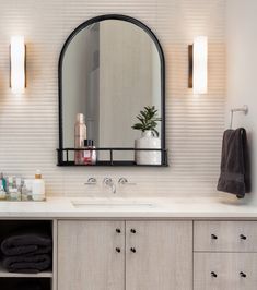 a bathroom with a sink, mirror and towels on the shelf in front of it